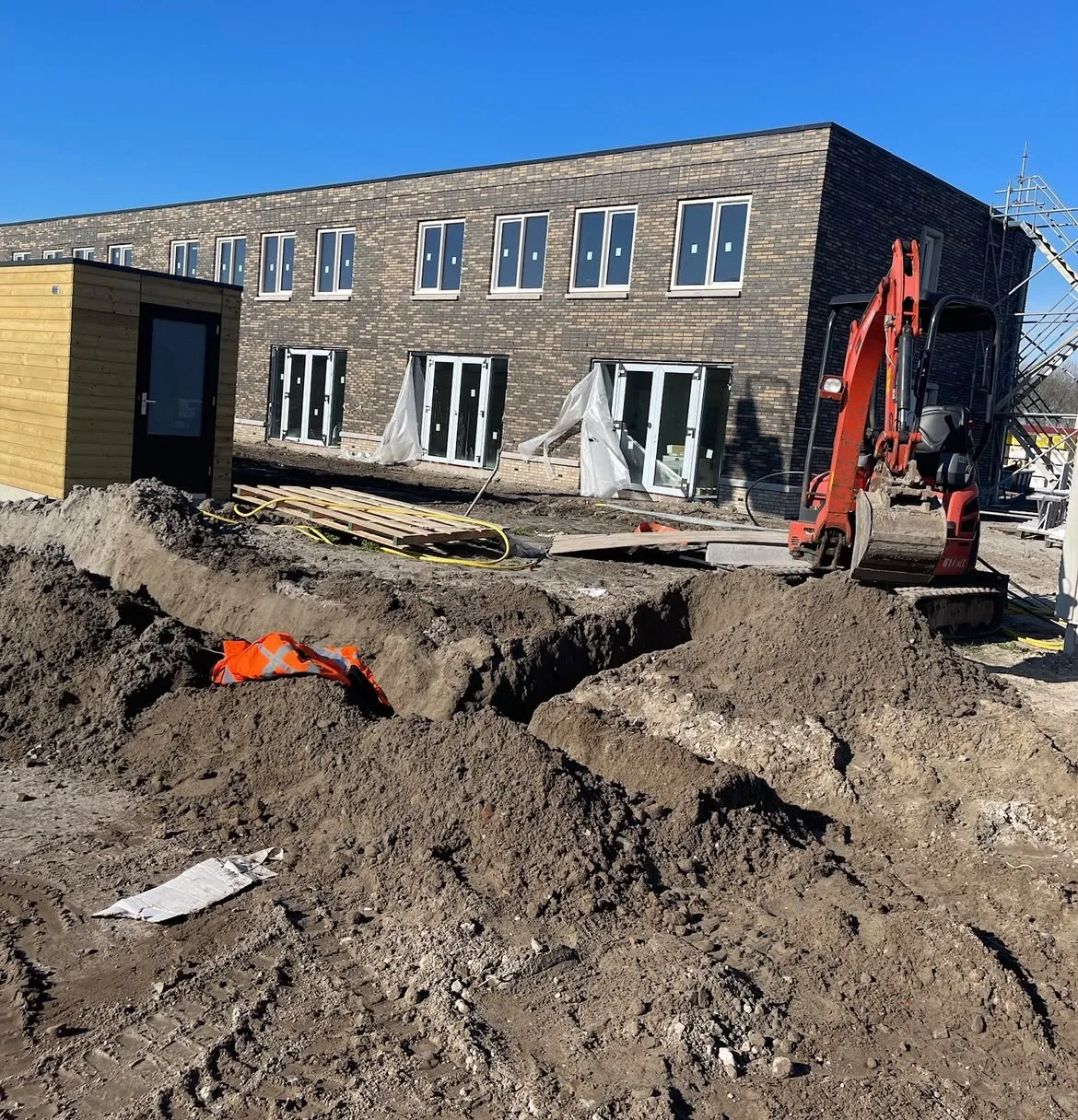 Open kabelsleuf langs een gebouw in de zon